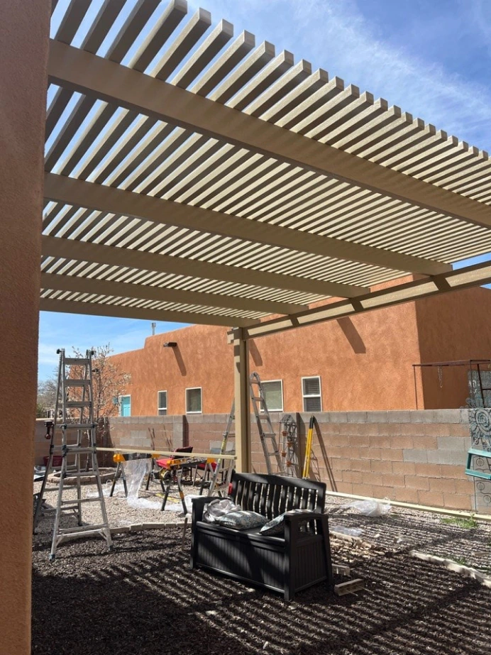 Aluminum pergola with slatted roof shading a backyard seating area in Albuquerque